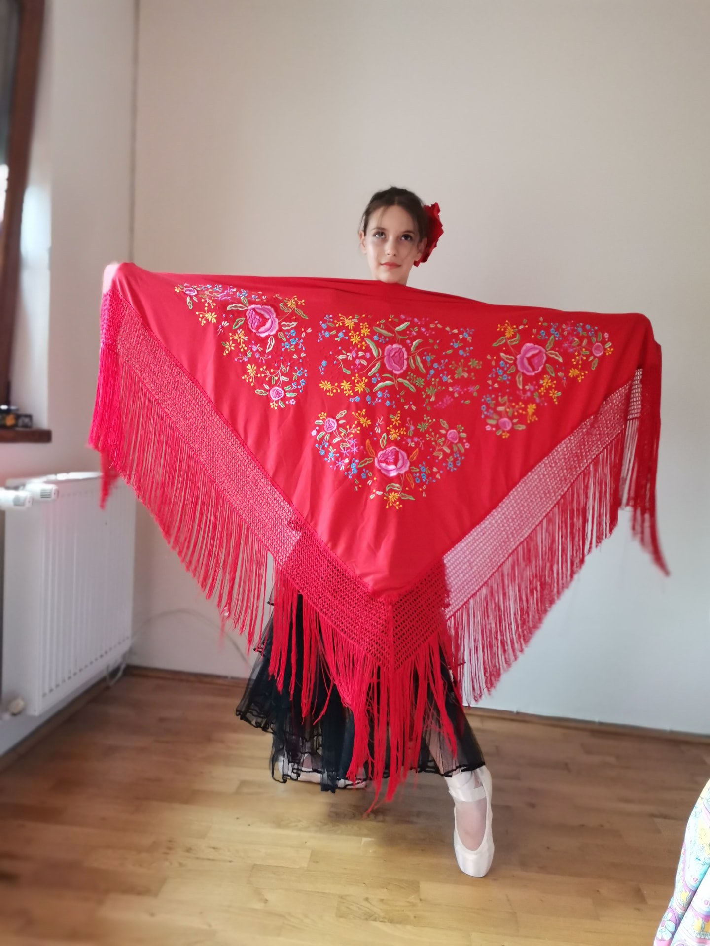 Tânără dansatoare prezentând un șal roșu brodat